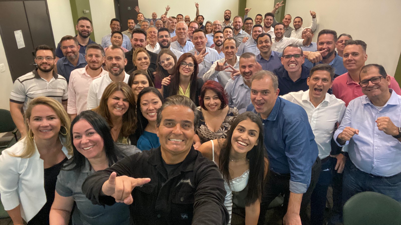 Jordão sorrindo com um grupo de participantes reunidos após uma palestra
